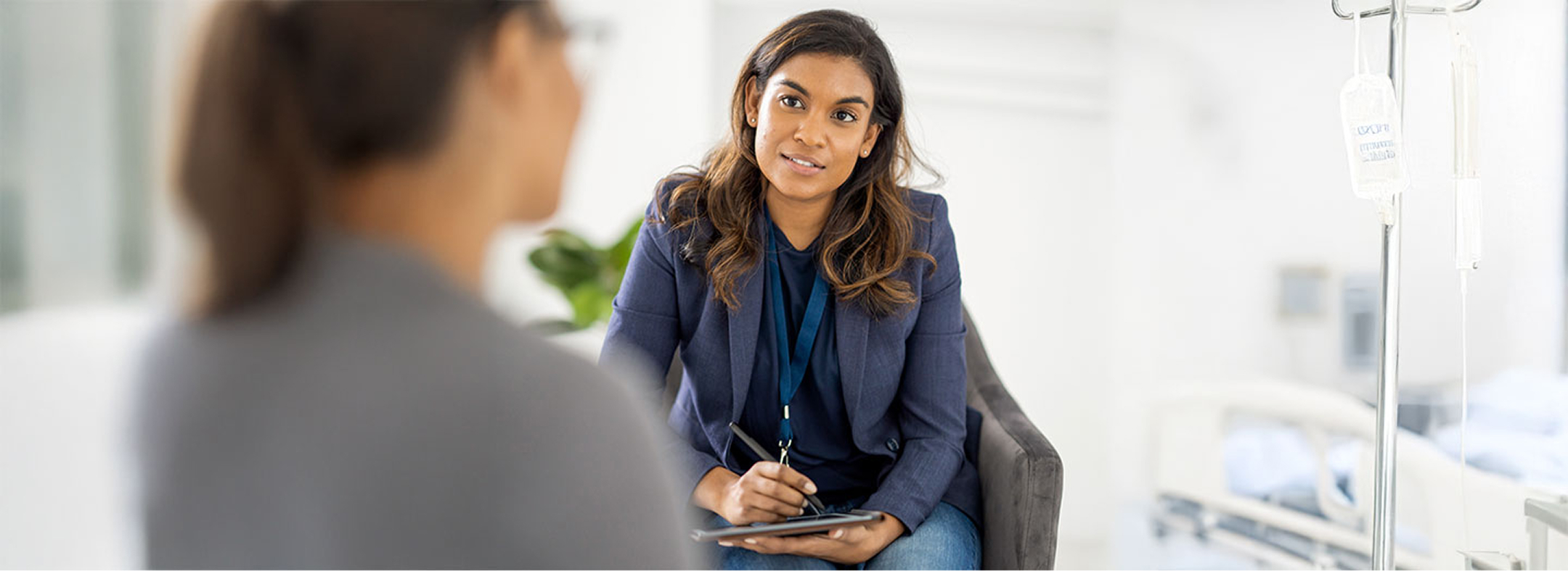 woman in blue blazer talking to someone while taking notes