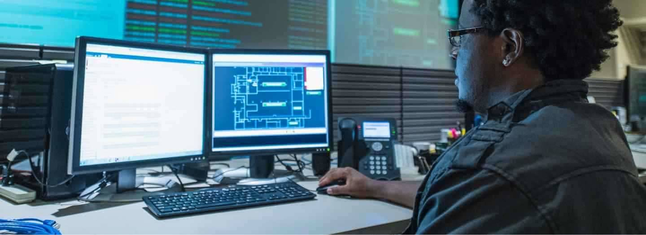 man looking at a computer with two monitors