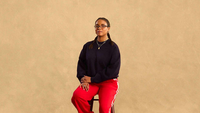 woman in black sweater and red pants sitting on a stool