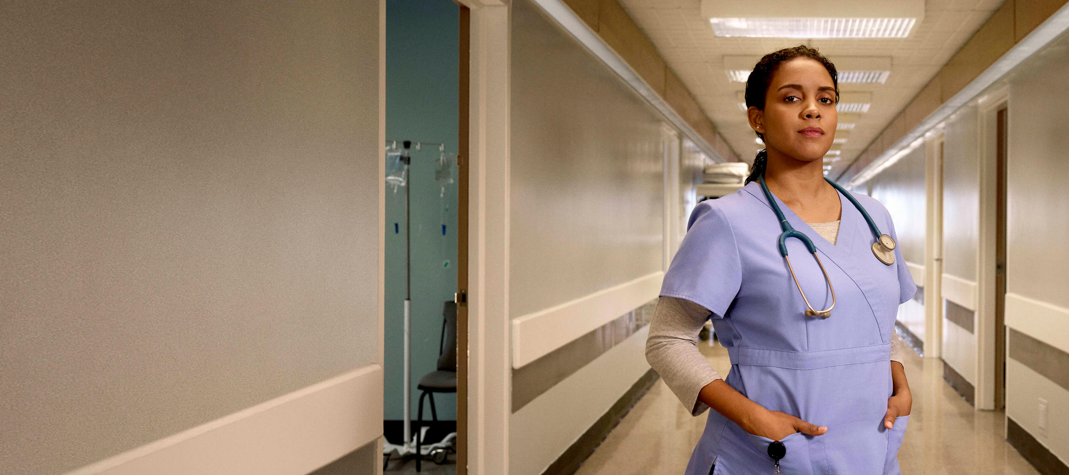 female nurse in scrubs standing confidently with a stethescope around her neck 