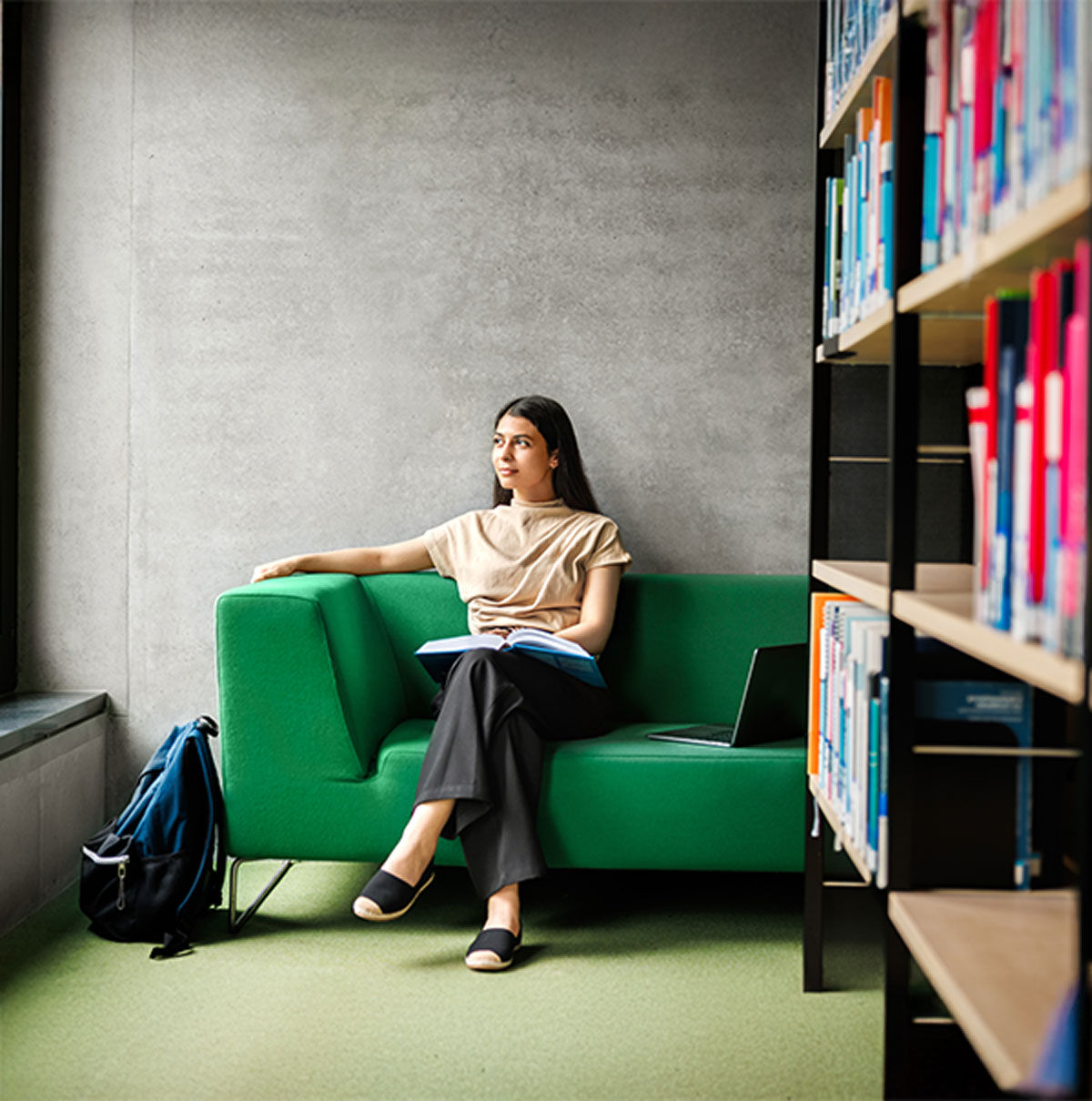 woman sitting on large green sofa with a book