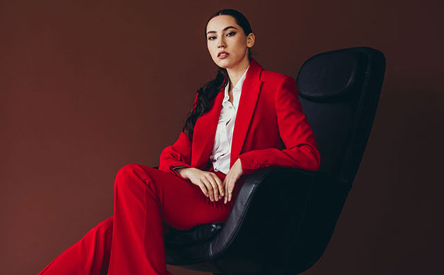 asian woman in bright red suite sitting in a leather chair