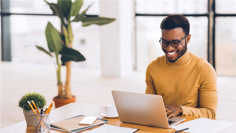 man in yellow sweater working on laptop