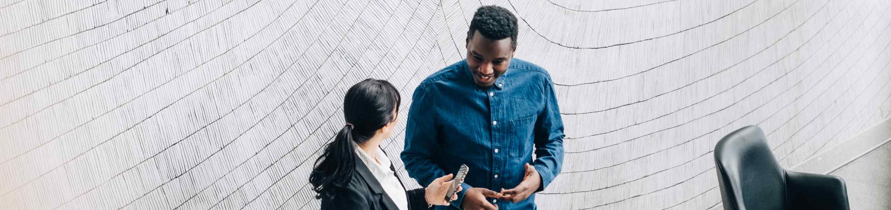 woman and man talking by a large stone grey wall