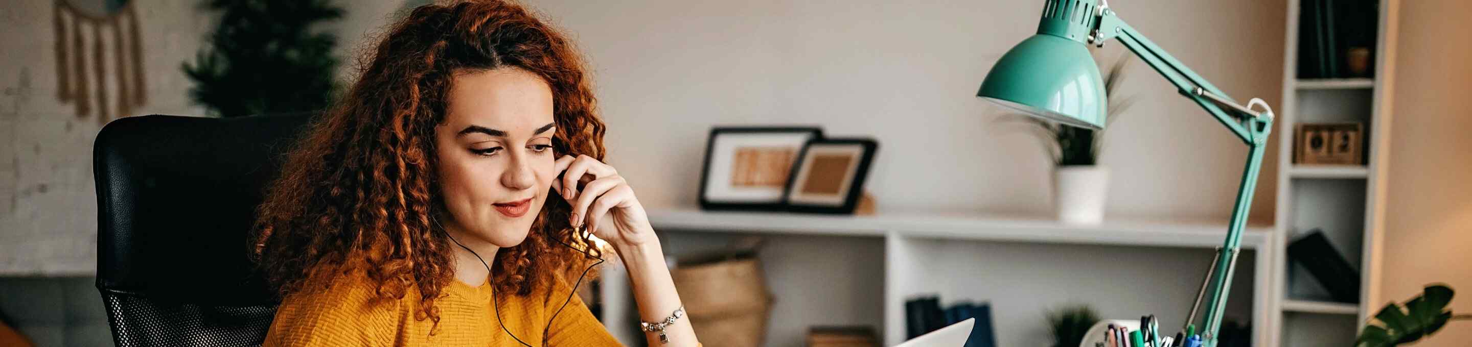 woman in yellow sweater taking notes in her home office