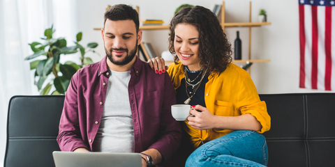 couple on sofa at laptop flag in background